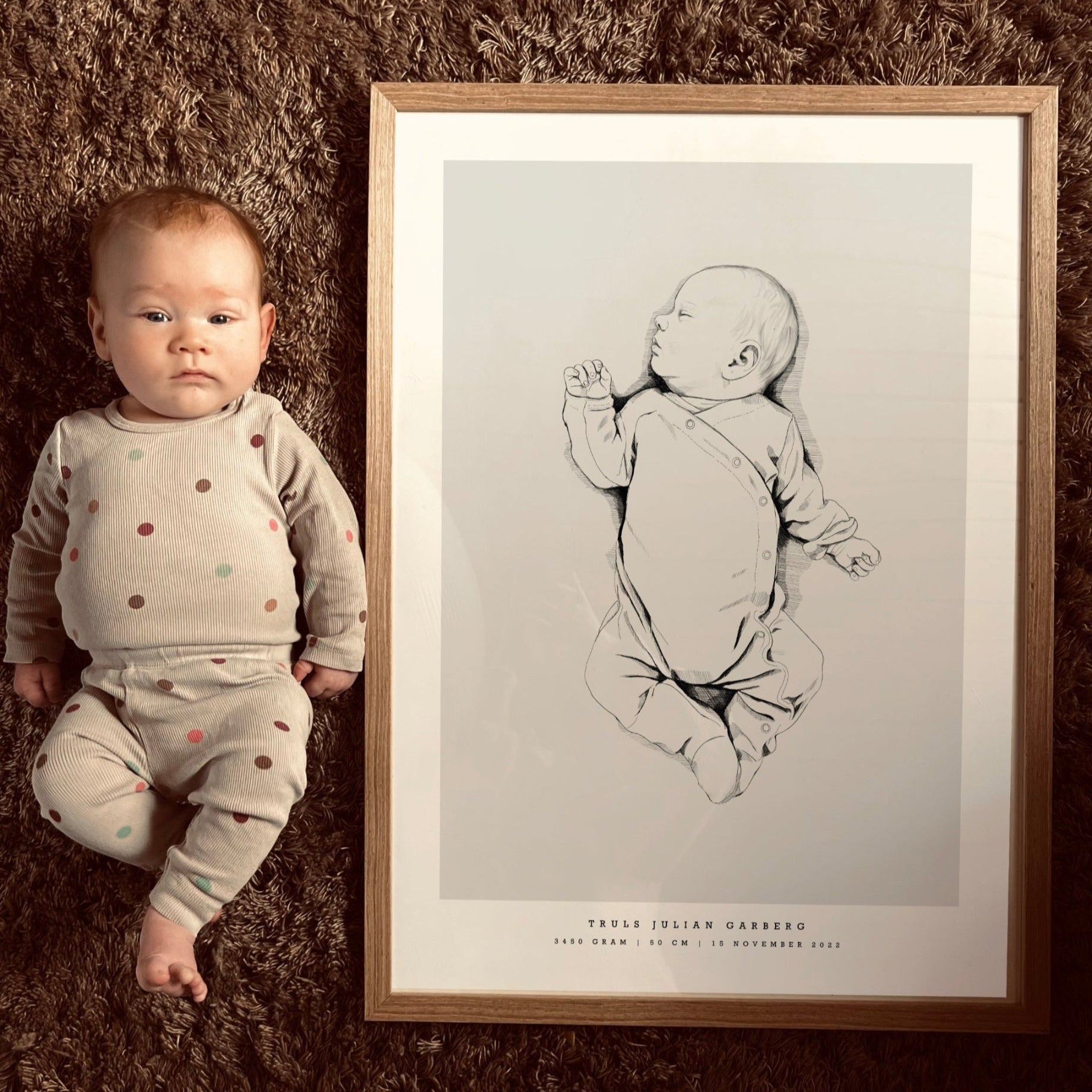 Baby lying next to their hand-drawn birth poster on a soft surface