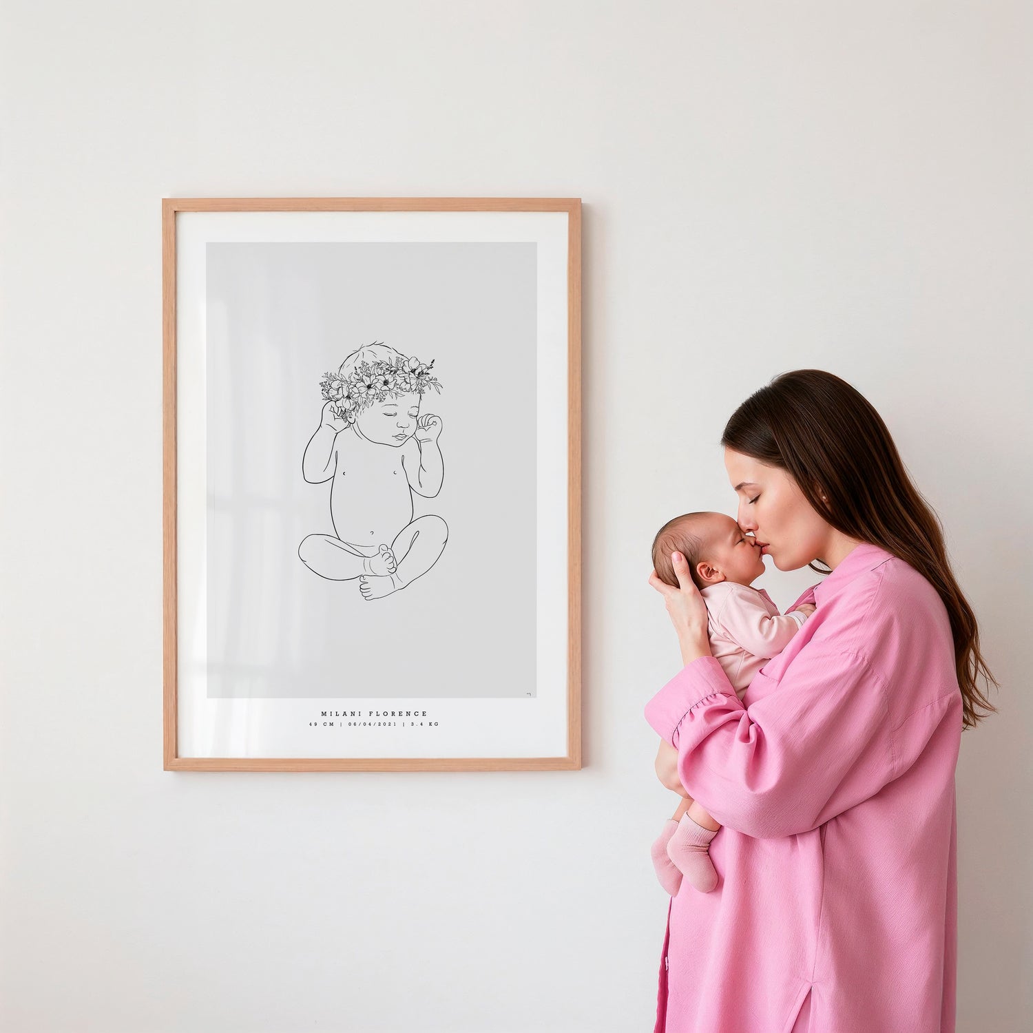 Mamma pussar sin bebis bredvid en födelsetavla med blomkrans. Mother kissing her baby next to a birth poster adorned with a flower crown.