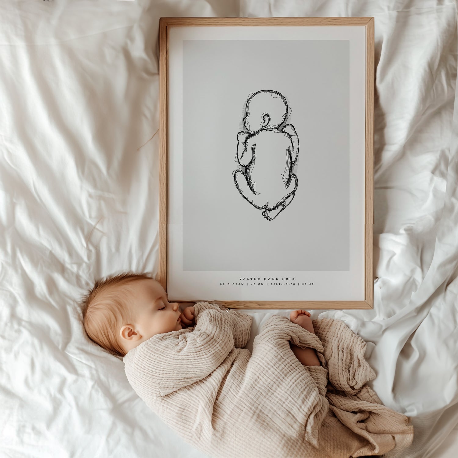 Bebis som ligger bredvid sin personliga födelsetavla i barnrummet. Baby lying next to their personalized birth poster in the nursery.