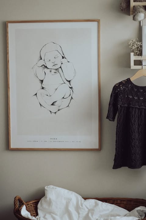 Custom hand-drawn birth poster hanging on the wall in a cozy nursery
